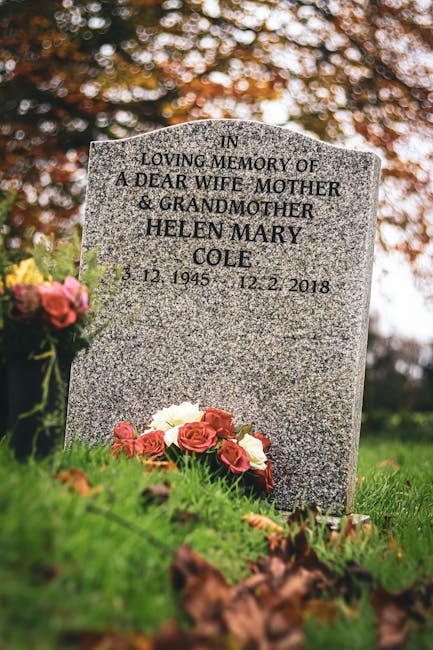 A gray polished granite headstone with engraved black lettering dedicated to Helen Mary Cole, a beloved wife, mother, and grandmother, set in a well-maintained cemetery. In front of the headstone, the